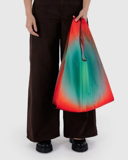 Person holding a colorful gradient bag with black pants on a white background
