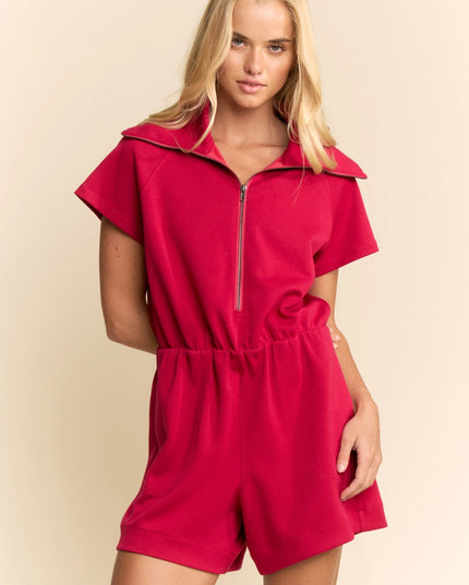 Woman wearing a red romper against a beige background