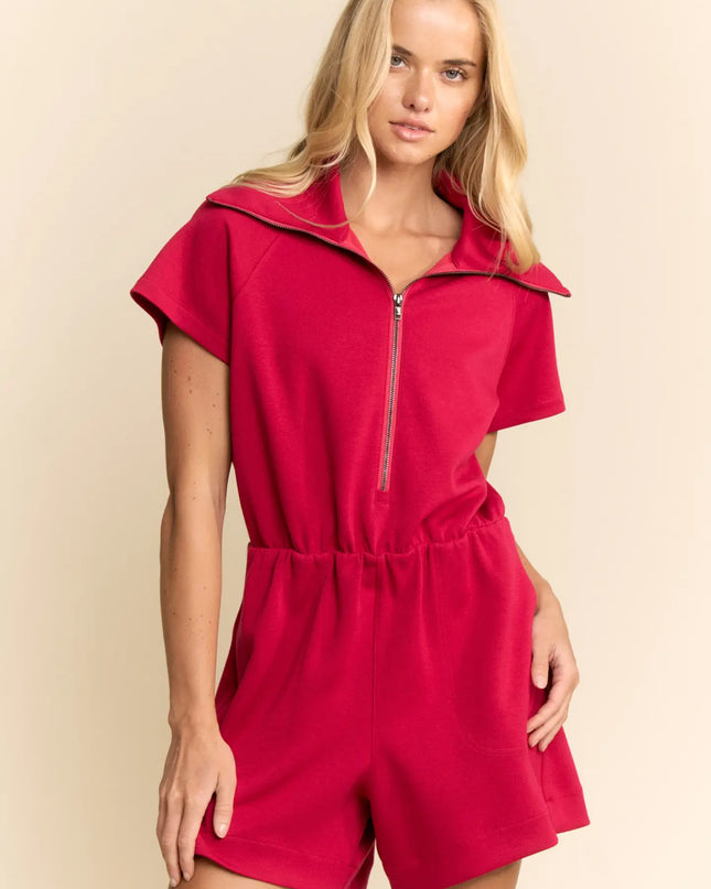 Woman wearing a red romper with a zipper on a beige background