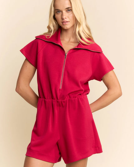 Woman wearing a red romper against a beige background