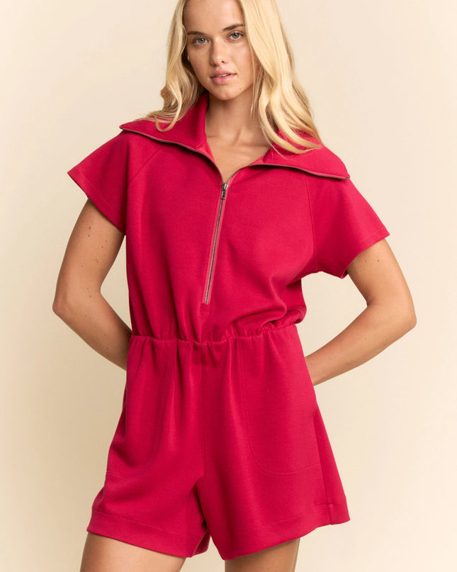 Woman wearing a red romper against a beige background