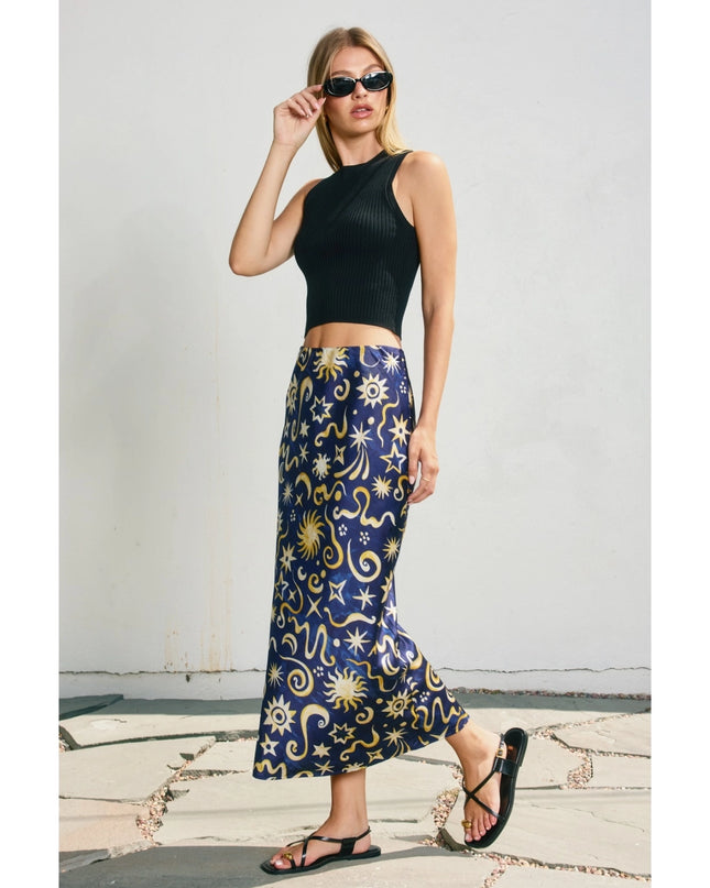 Woman wearing a black top and a long, patterned skirt with sun and moon designs.