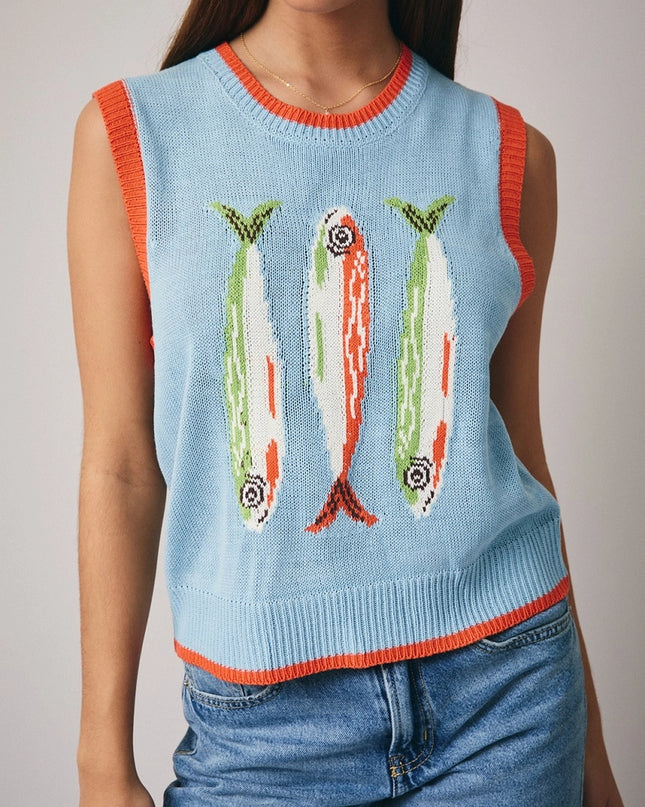 Woman wearing a light blue sleeveless sweater with fish designs on a plain background