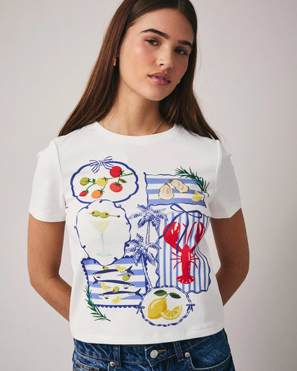 Woman wearing a white t-shirt with colorful graphics on a plain background