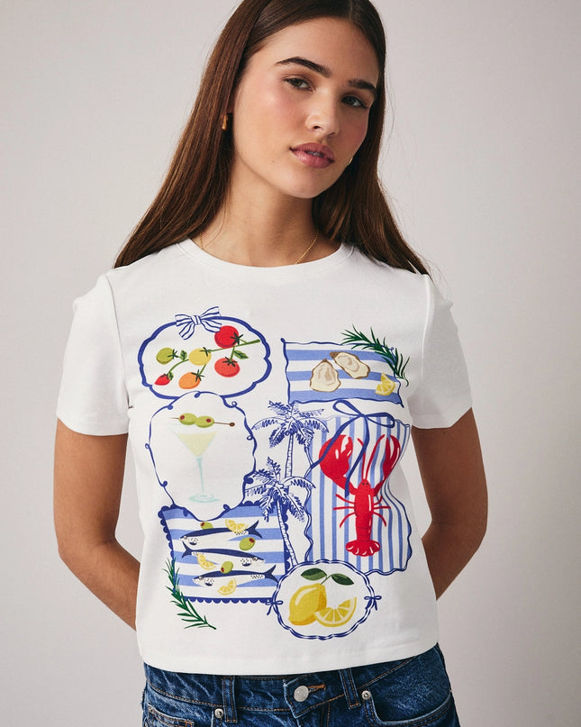 Woman wearing a white t-shirt with colorful graphics on a plain background