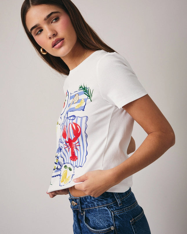 Woman wearing a white t-shirt with colorful graphic design on a plain background