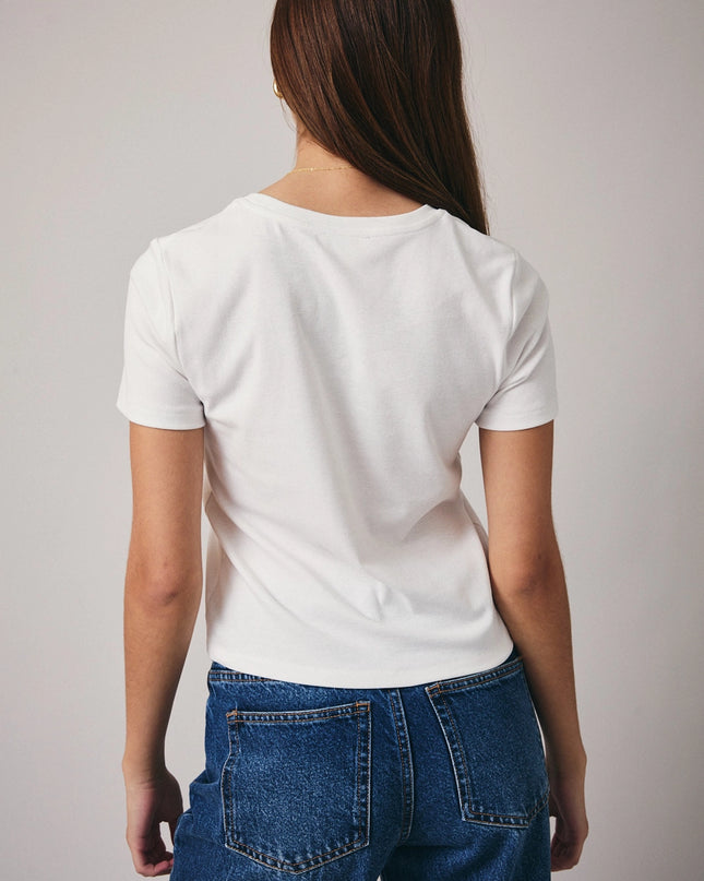 Person wearing a plain white t-shirt and blue jeans on a light gray background