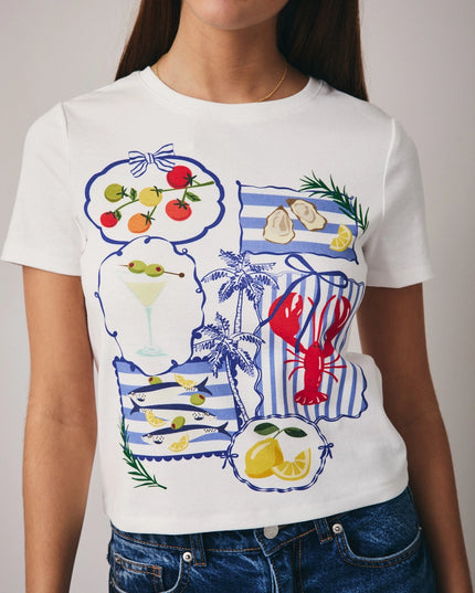 Person wearing a white t-shirt with colorful graphics, including a lobster and lemon, on a plain background.