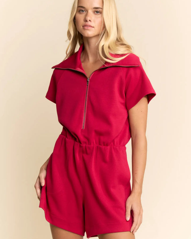 Woman wearing a red romper against a beige background