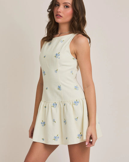 Woman wearing a light-colored dress with floral patterns on a plain background