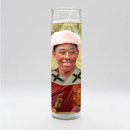 Candle with a printed design of a person wearing a pink hat and red robe on a white background