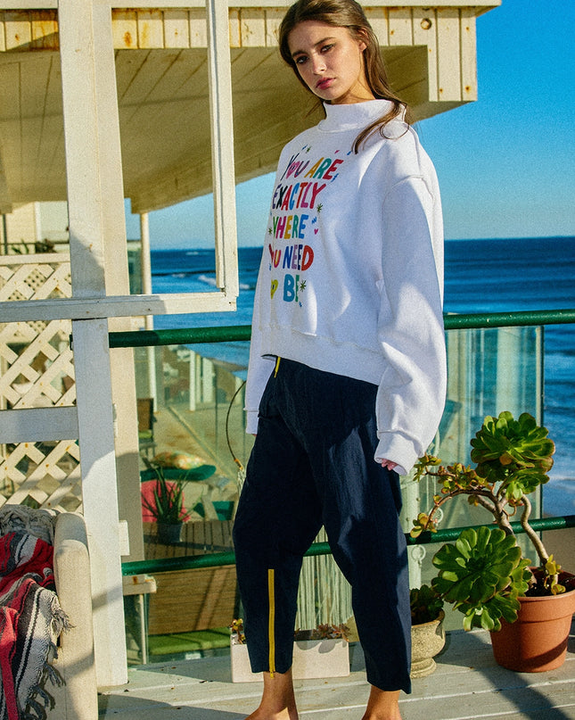 Woman wearing a colorful sweatshirt on a balcony with ocean view